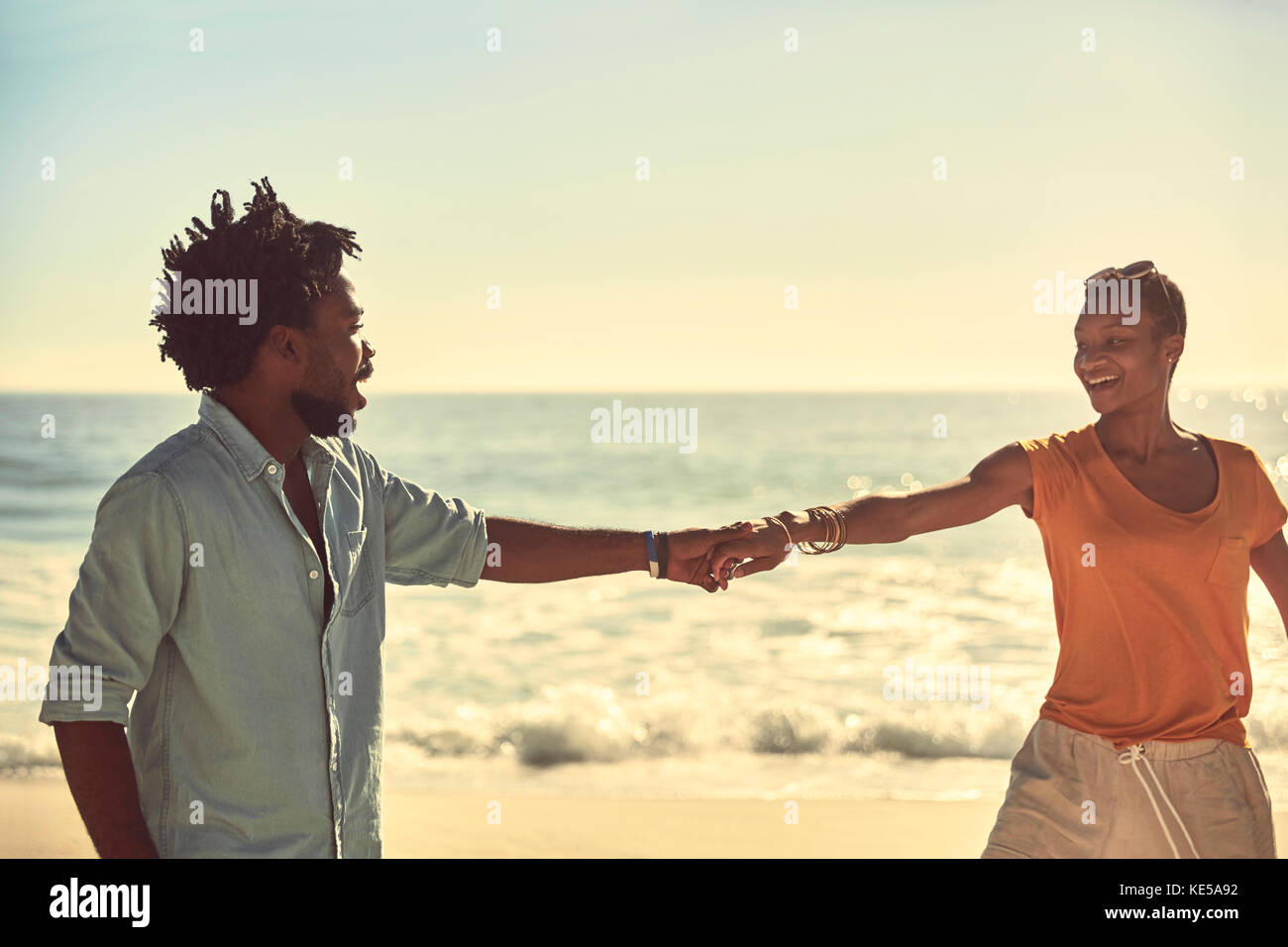 Jeune couple affectueux tenant les mains sur la plage ensoleillée d'été Banque D'Images