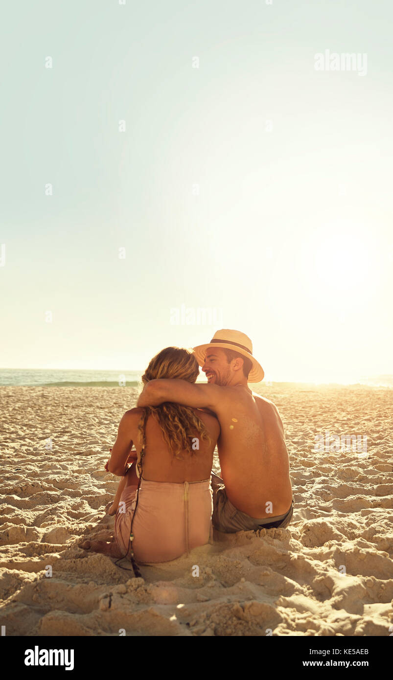 Un jeune couple affectueux qui s'enserre sur une plage ensoleillée d'été Banque D'Images