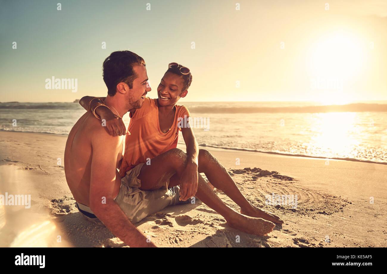 Un jeune couple affectueux qui s'embrasse sur une plage ensoleillée de l'océan en été Banque D'Images