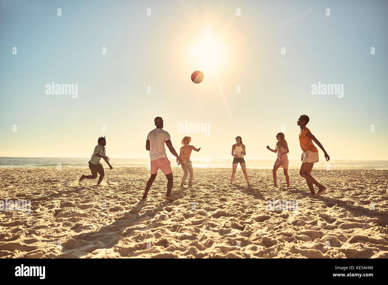 Jeunes amis jouant avec un ballon de plage sur une plage ensoleillée d'été Banque D'Images