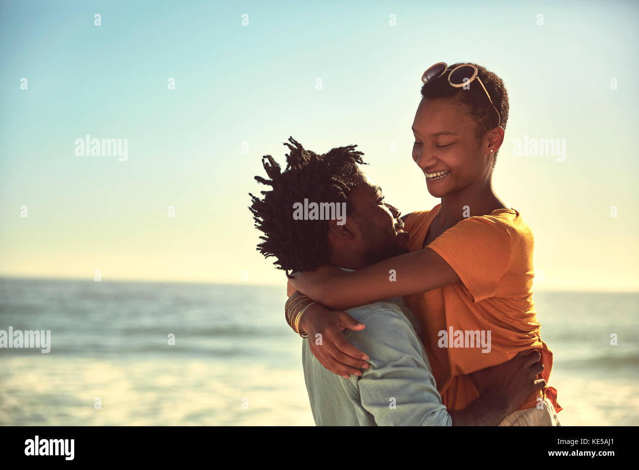 Un jeune couple affectueux qui s'enserre sur une plage ensoleillée d'été Banque D'Images