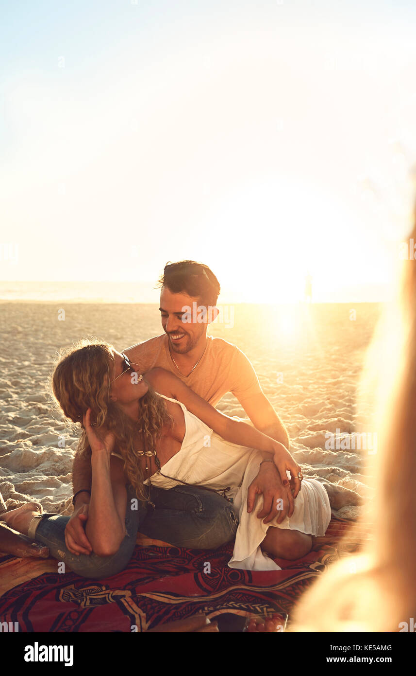 Un jeune couple affectueux se détendant sur une plage ensoleillée d'été Banque D'Images
