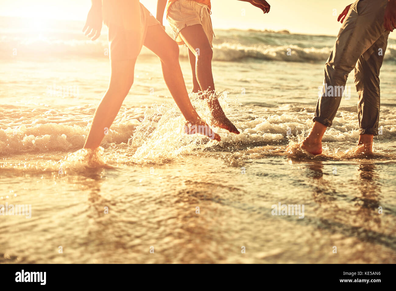 De jeunes amis éclaboussant dans le soleil de l'été sur l'océan Banque D'Images