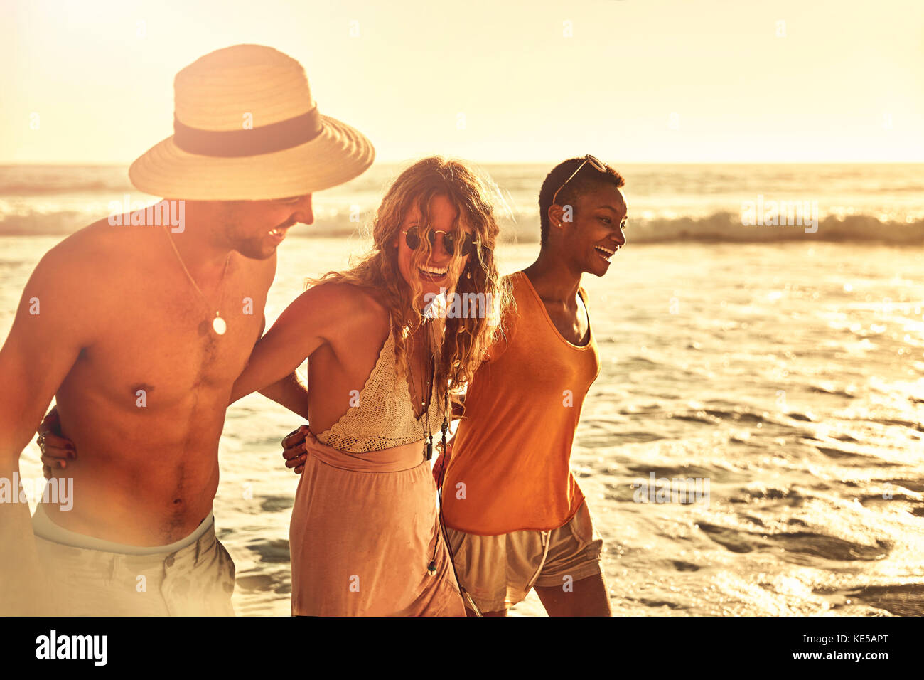 Rire de jeunes amis marchant sur la plage ensoleillée d'été sur l'océan Banque D'Images