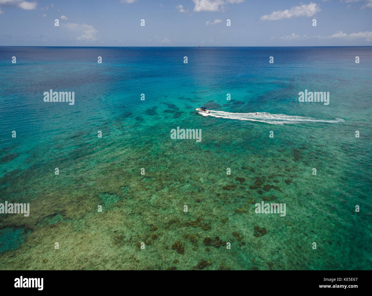 Un skieur de l'eau passe au-dessus d'un récif à mullins beach sur l'île antillaise de la Barbade. Banque D'Images