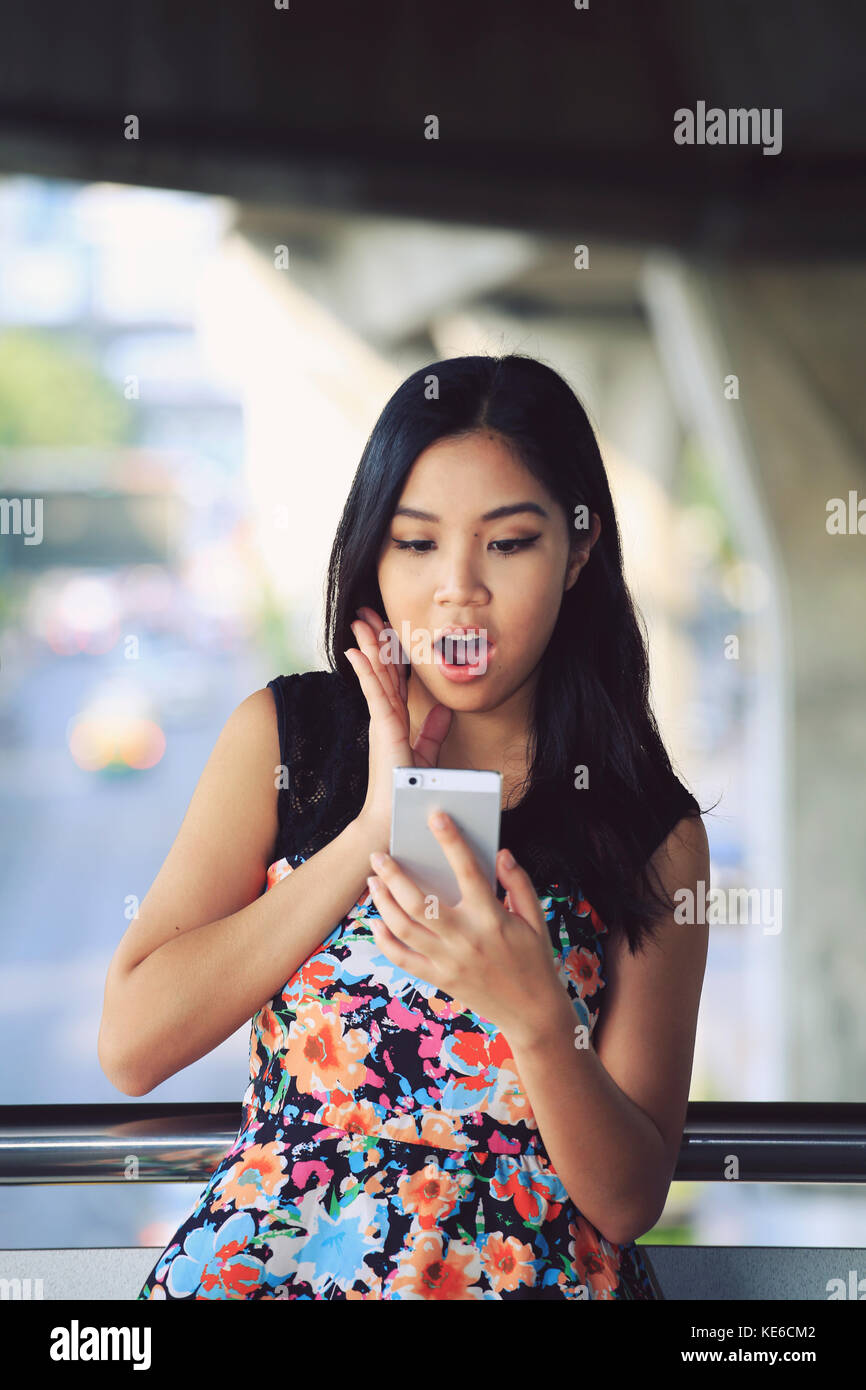 Jeune femme choquée par message texte sur son téléphone portable Banque D'Images