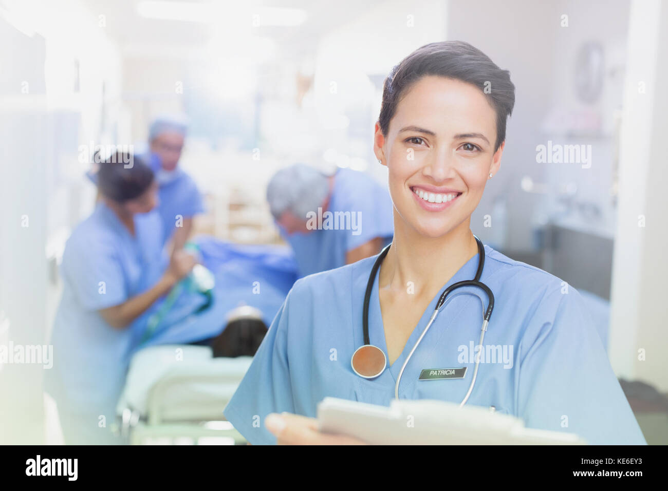 Portrait femme souriante et confiante chirurgien avec presse-papiers dans le couloir de l'hôpital Banque D'Images
