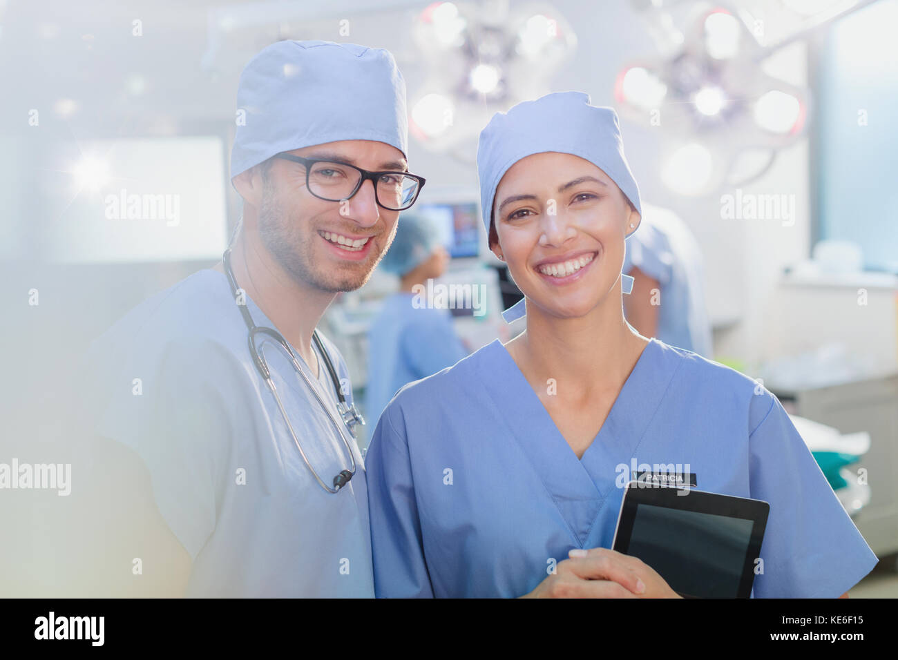 Portrait des chirurgiens souriants et confiants avec une tablette numérique dans la salle d'opération Banque D'Images