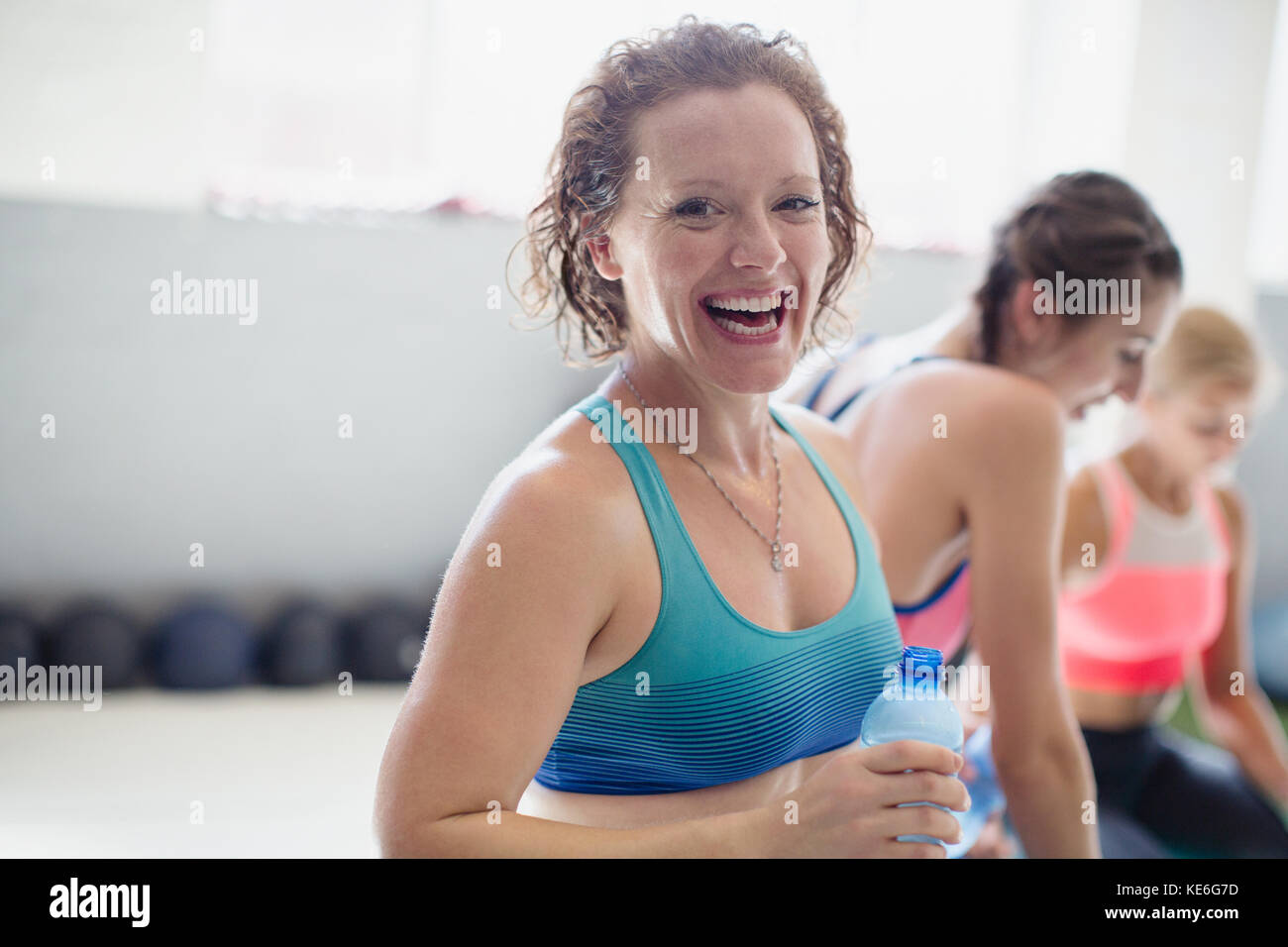 Portrait souriant, riant femme de boire de l'eau et de repos après l'entraînement à la salle de gym Banque D'Images