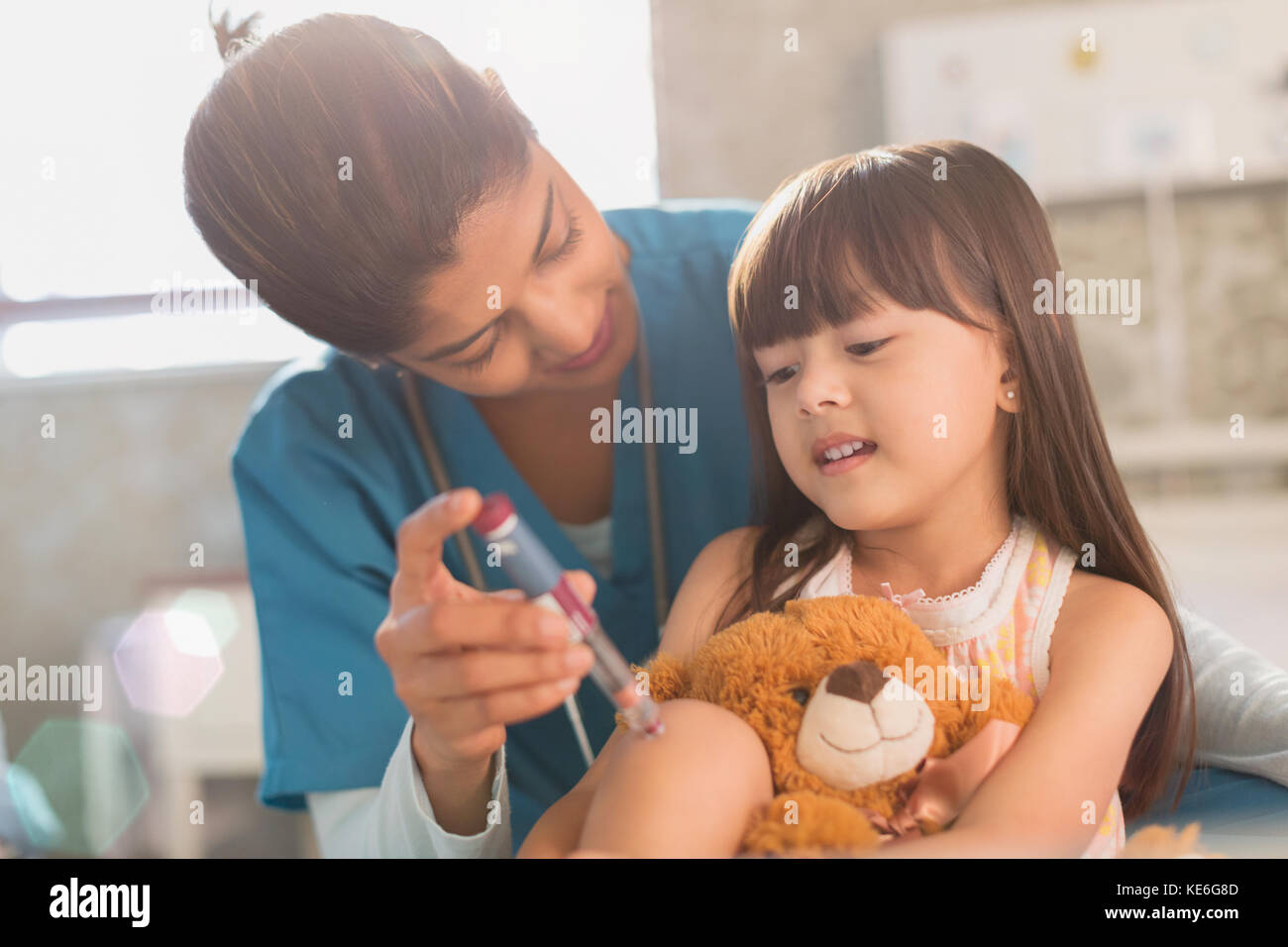 Infirmière féminine enseignant jeune fille patient avec ours en peluche comment utilisez un stylo à insuline Banque D'Images