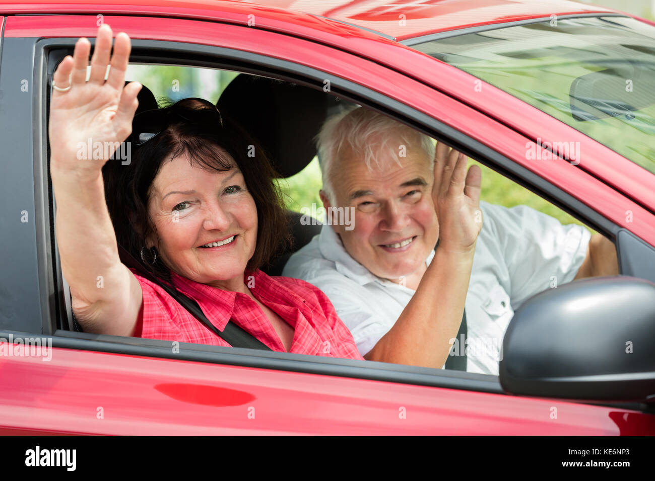 Happy Senior couple assis à l'Intérieur voiture Waving Goodbye Banque D'Images