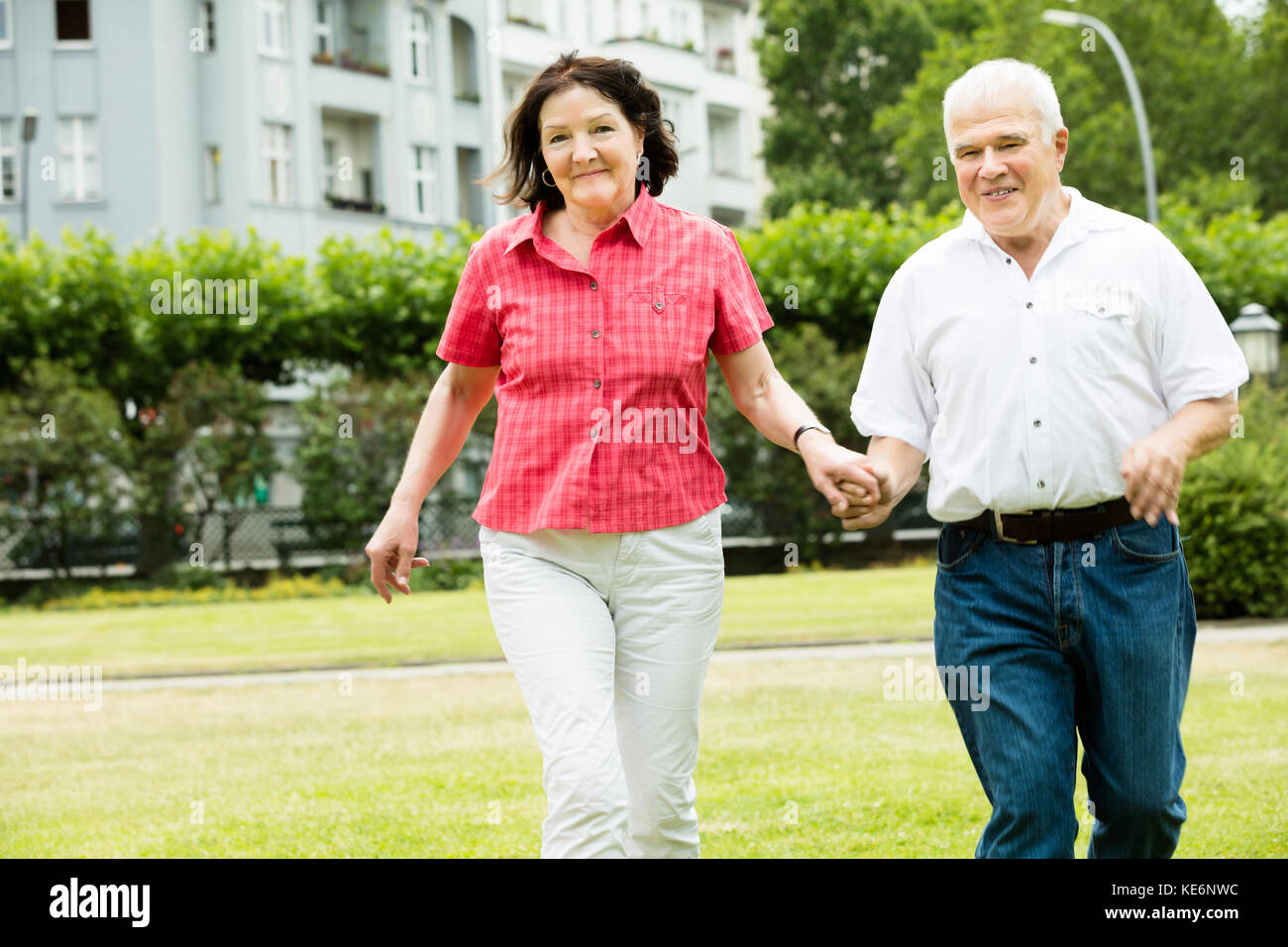 Happy Senior Couple Holding Hands Running in Park Banque D'Images