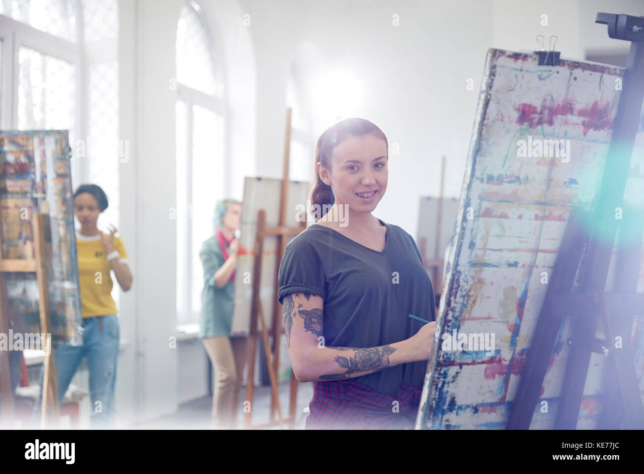 Portrait femme peintre souriante avec tatouages peinture en classe d'art studio Banque D'Images