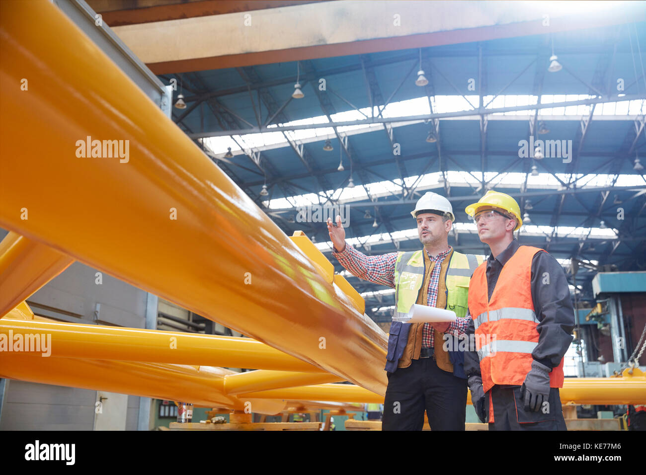 Contremaître mâle avec presse-papiers expliquant au travailleur en usine Banque D'Images