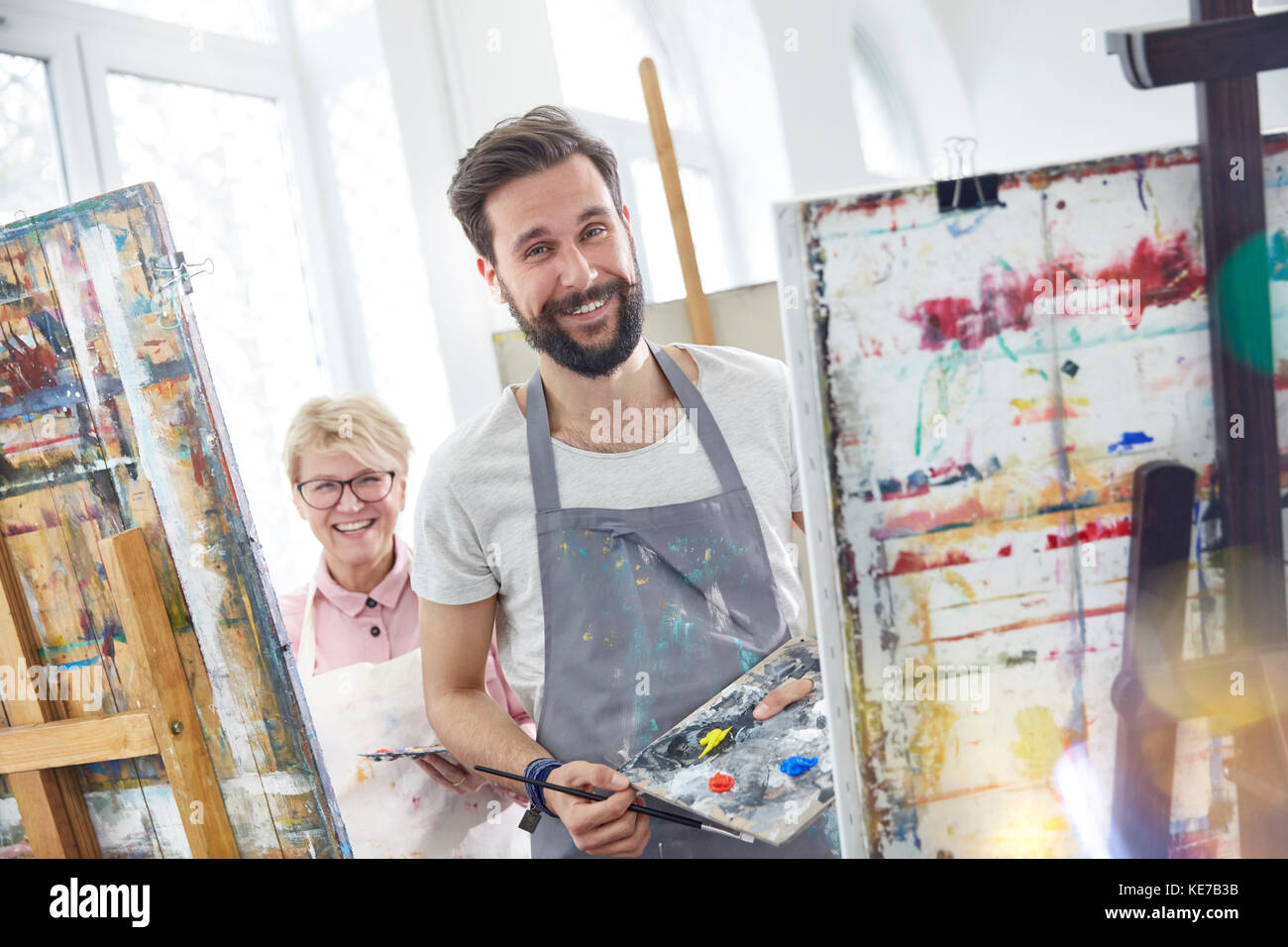 Portraits souriants artistes peignant sur des chevalets dans un studio de classe artistique Banque D'Images