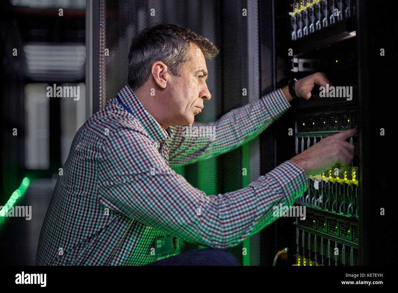 Un technicien INFORMATIQUE spécialisé travaillant sur un panneau dans un serveur sombre chambre Banque D'Images