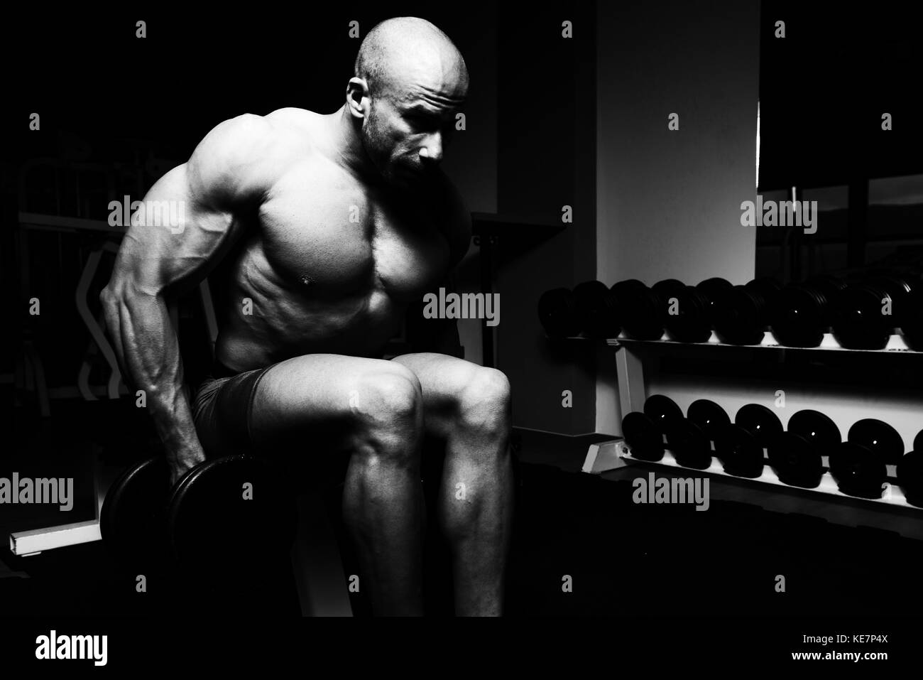 Bodybuilder sérieux faisant Poids lourd l'exercice pour le trapezius with Dumbbells Banque D'Images