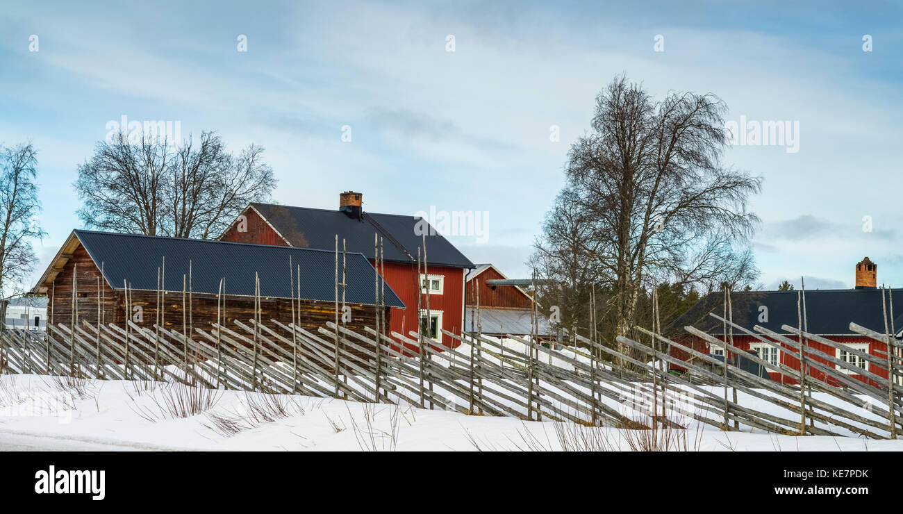 Une clôture, une ferme avec bâtiments de ferme rouge en hiver ; Arjeplog, Suède, comté de Norrbotten Banque D'Images