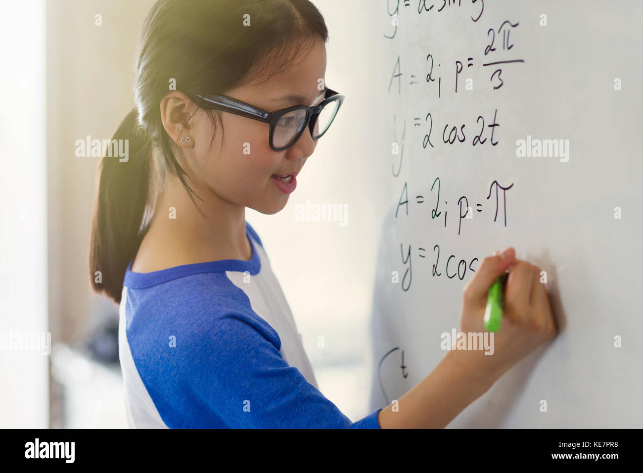 Portrait souriant, confiante jeune élève résolvant des équations physiques au tableau blanc en classe Banque D'Images