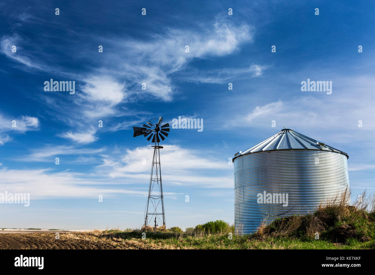 Un ancien moulin à vent avec une grande trémie métallique avec ciel bleu et nuages intéressants ; Beiseker, Alberta, Canada Banque D'Images