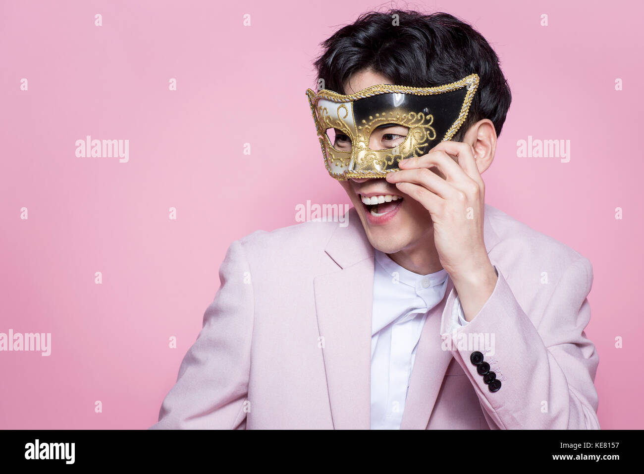 Portrait of young smiling man en costume rose portant un masque Banque D'Images