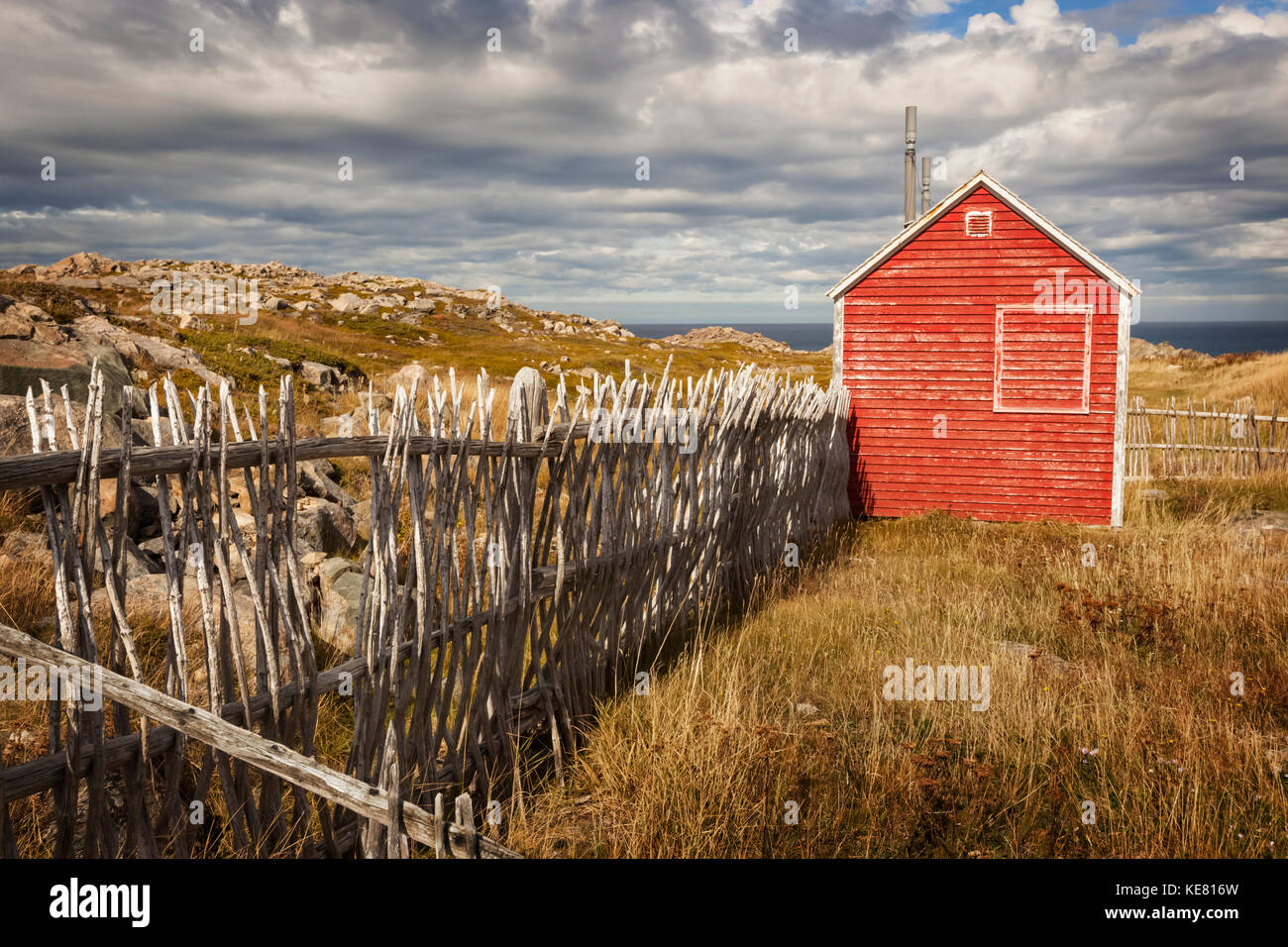 Un petit hangar en bois rouge à côté d'une clôture le long de la côte ; Terre-Neuve, Canada Banque D'Images