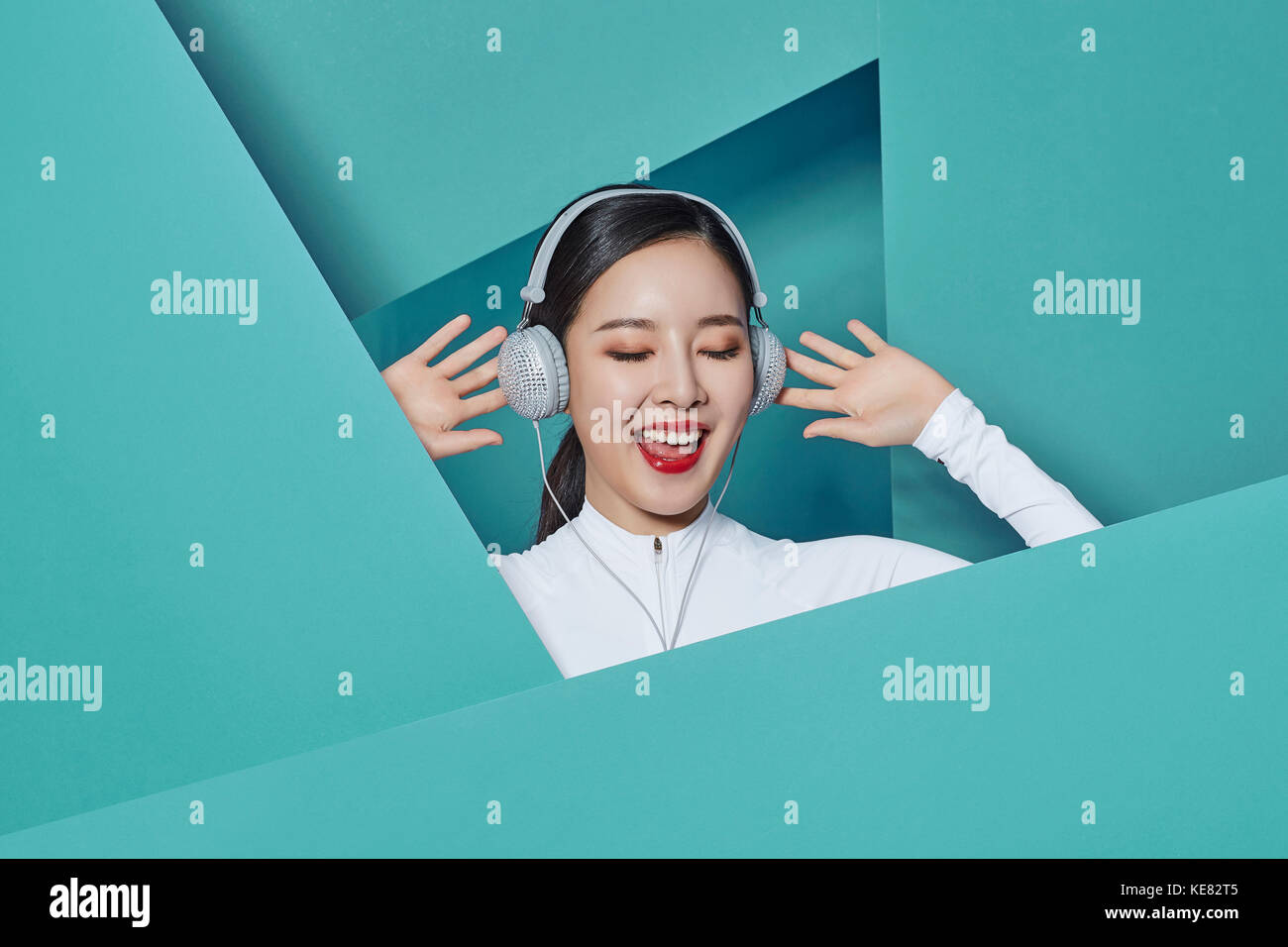 Portrait of young smiling woman listening to music fermant les yeux Banque D'Images