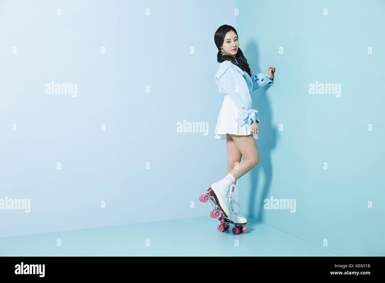 Jeune femme posant en patins à debout sur un pied Banque D'Images