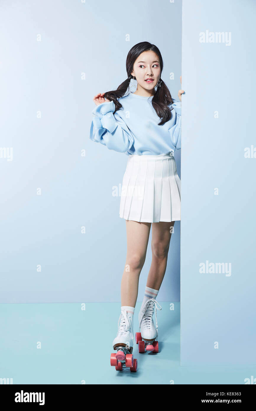 Jeune femme en patins à poser à côté Banque D'Images