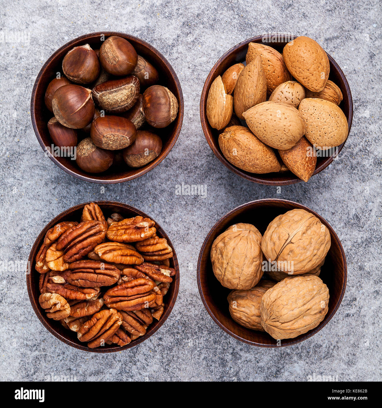 Amandes, noix, noisettes entières ensemble et noix de pécan dans bol en bois avec fond en pierre. focus sélectif de la profondeur de champ. Banque D'Images