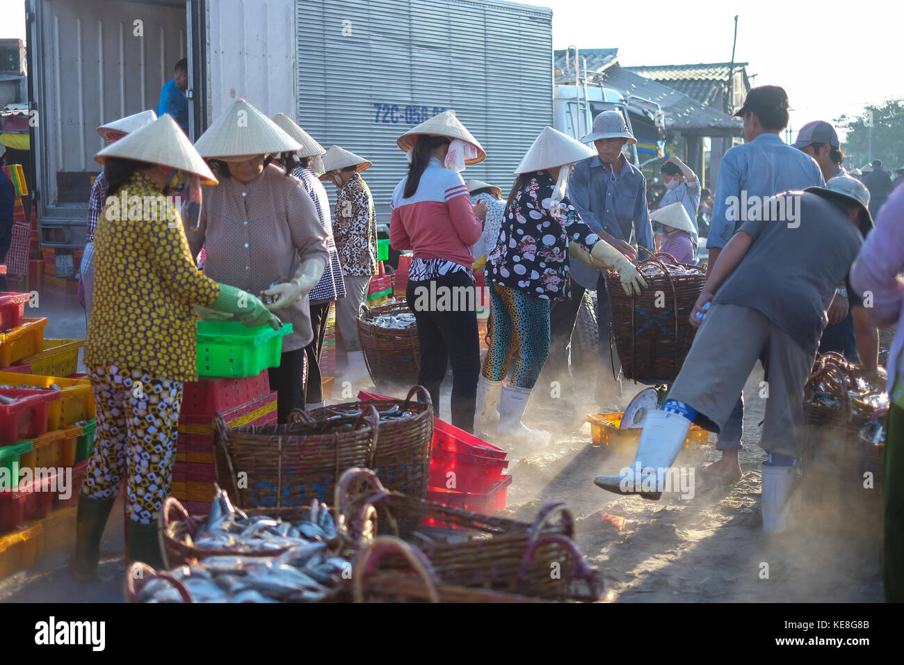 Local non identifié des personnes qui travaillent dans un marché, la femme et l'homme poissons est sélective, c'est effectuer panier de navire sur la plage. sunflare du flou Banque D'Images