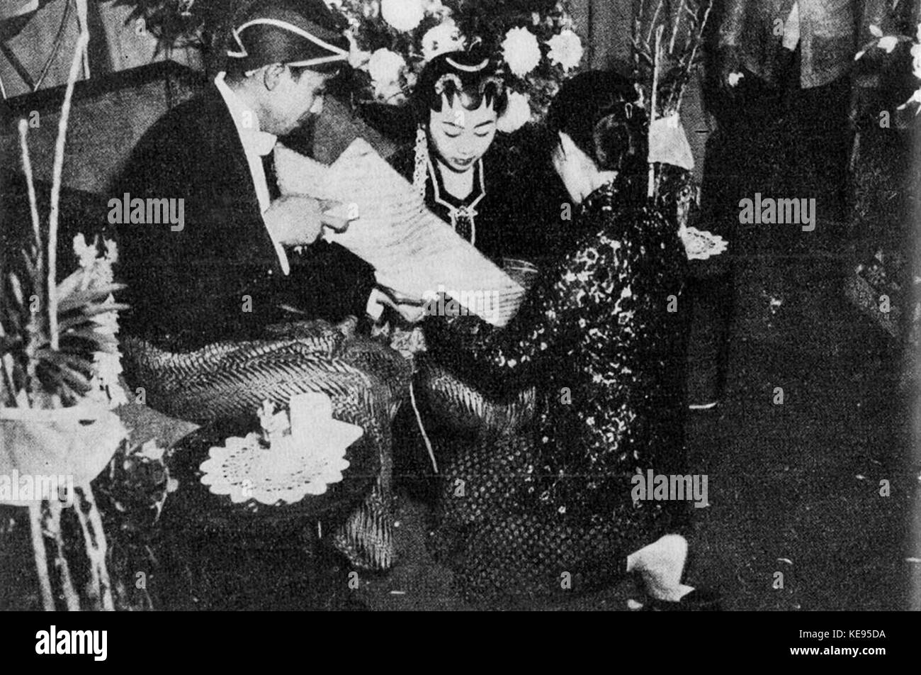 Cette image capture une cérémonie de mariage javanaise traditionnelle, où le marié verse du riz et des pièces dans le foulard de la mariée, symbolisant la prospérité et la bonne fortune pendant les rituels de mariage. Banque D'Images