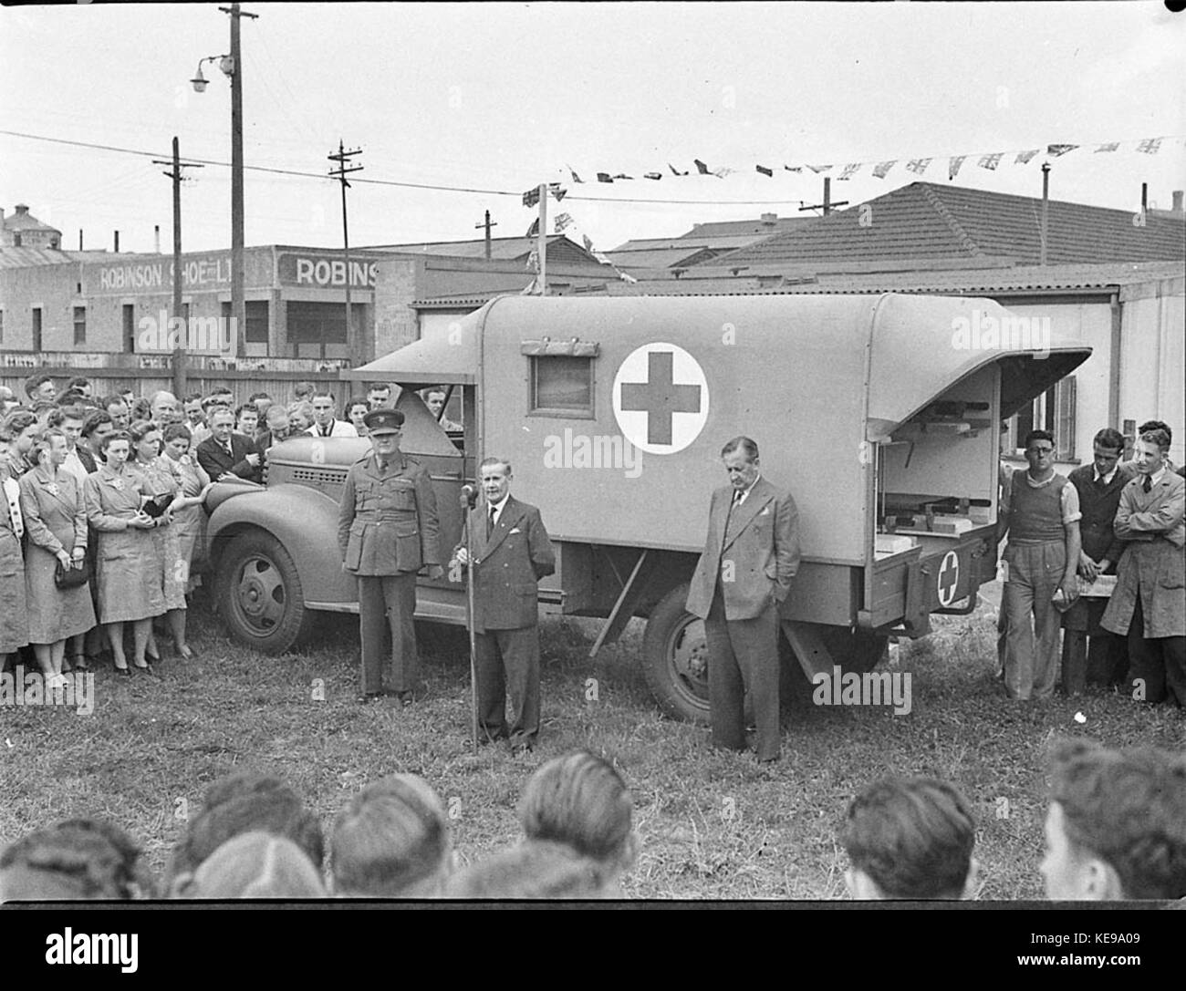 Cette image historique montre la présentation d'une ambulance par le personnel de Standard Telephone Cables, soulignant la responsabilité sociale de l'entreprise et le service communautaire. Banque D'Images