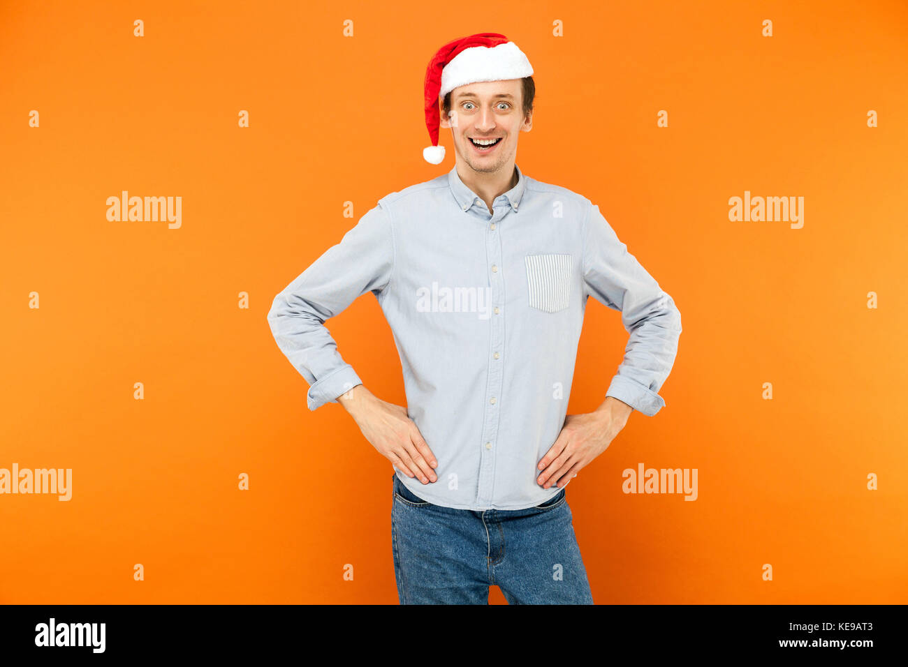 L'homme émotionnel Noël en rouge, les mains sur la ceinture, rugueux et sourire à la caméra en studio. Banque D'Images L'homme émotionnel Noël en rouge, les mains sur la ceinture, rugueux et sourire à la caméra en studio. Banque D'Images