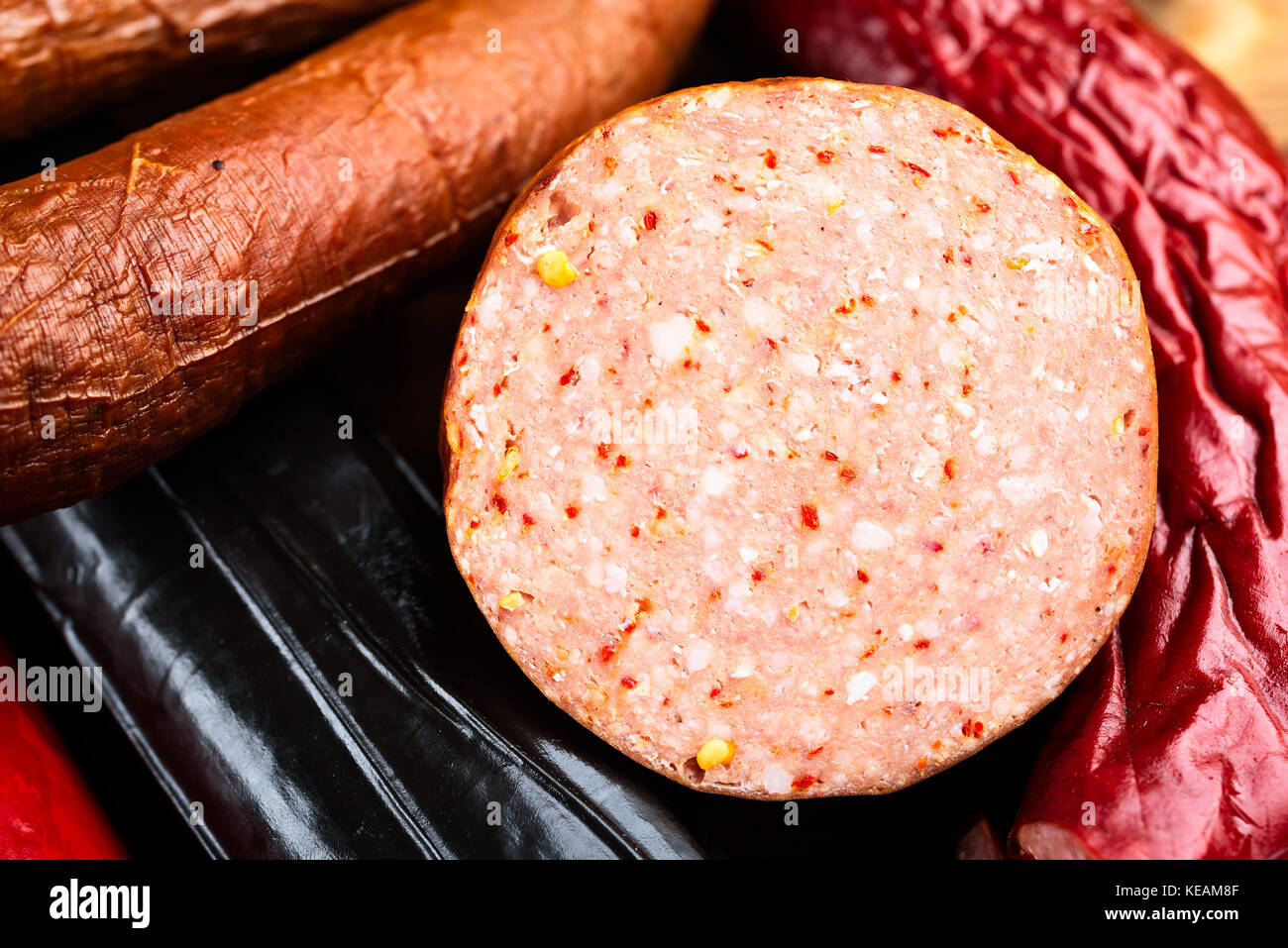 Délicieux morceau de saucisse fumée reposant sur d'autres saucisses dans l'arrière-plan. Ouvrir la surface de tranches de viande et d'épices montrer. Banque D'Images