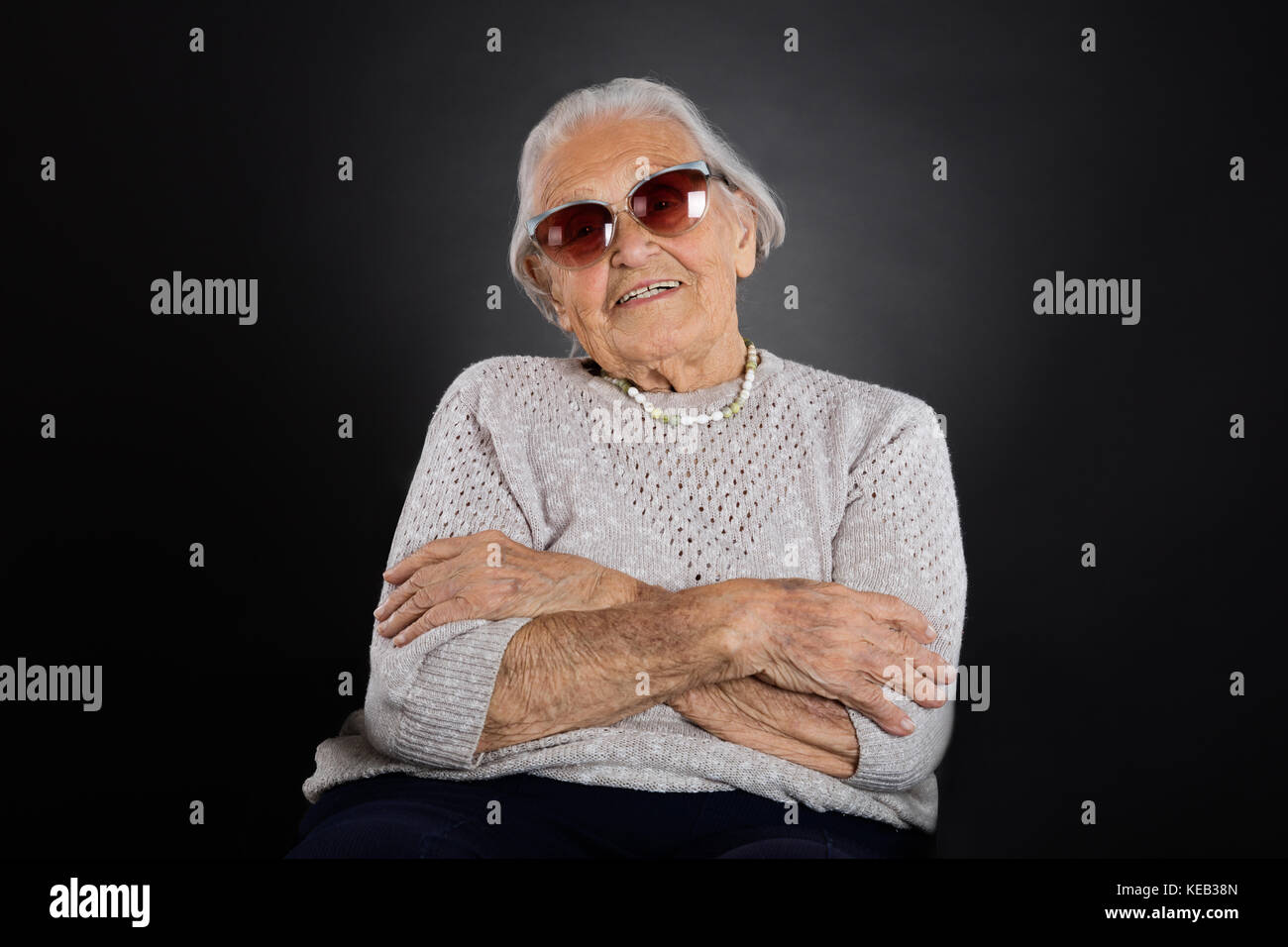 Portrait of senior woman with sunglasses sur fond gris Banque D'Images