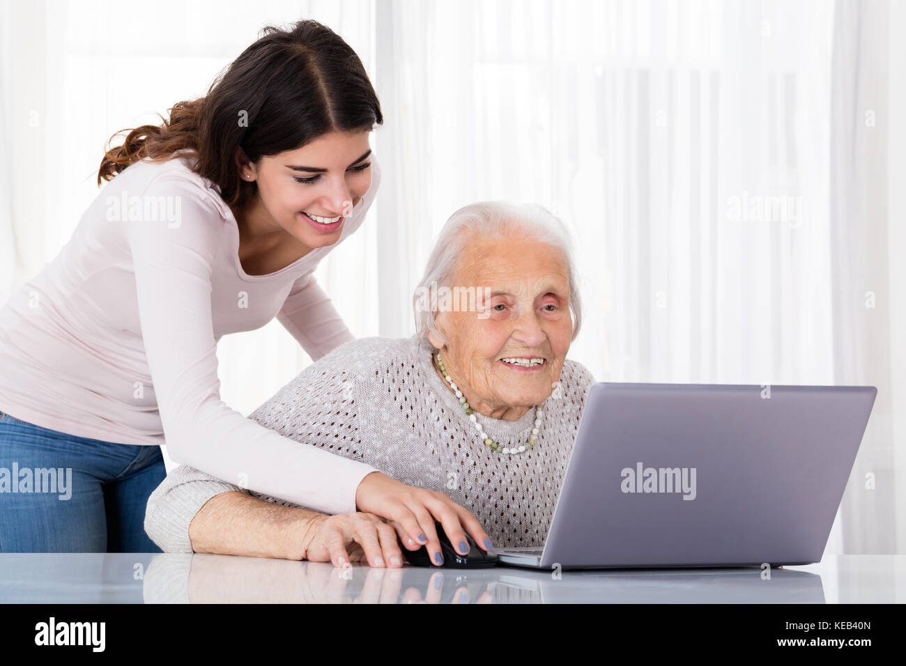 Jeune femme d'aider sa grand-mère pour l'aide d'un ordinateur portable sur un bureau à la maison Banque D'Images