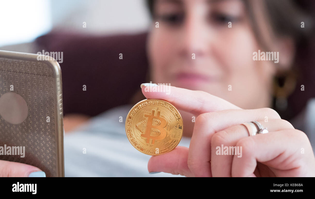 Young woman holding golden et de la saisie sur bitcoin close up smartphone Banque D'Images