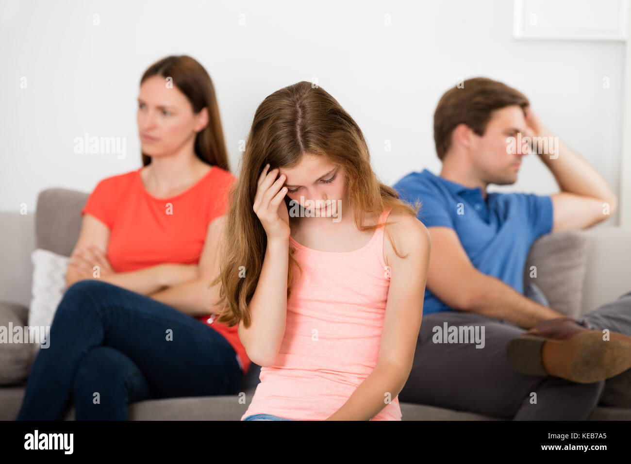 Upset Girl devant ses parents malheureux Sitting on Sofa Banque D'Images