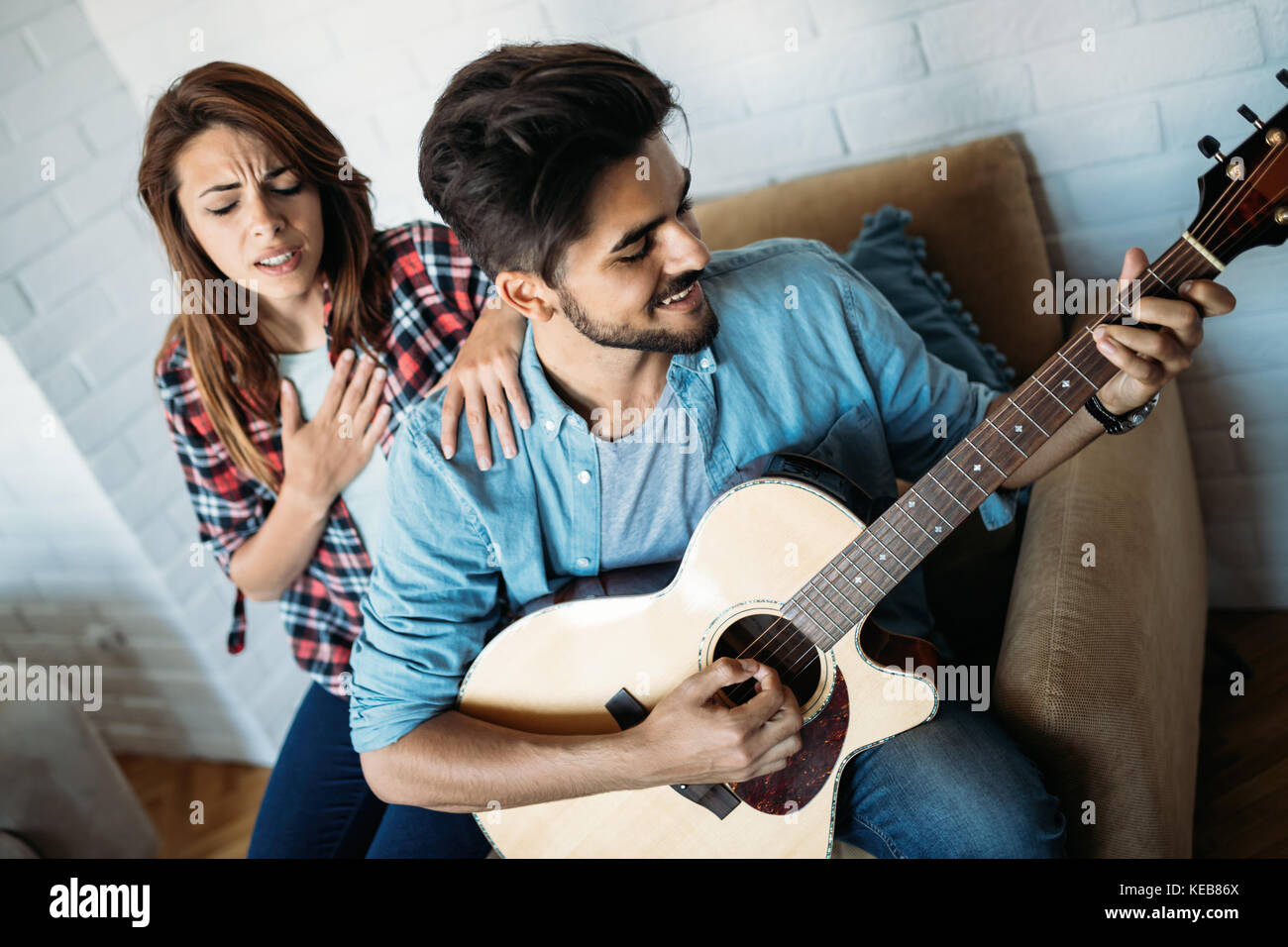 Beau jeune homme jouant de la guitare tandis que sa petite amie est le chant Banque D'Images