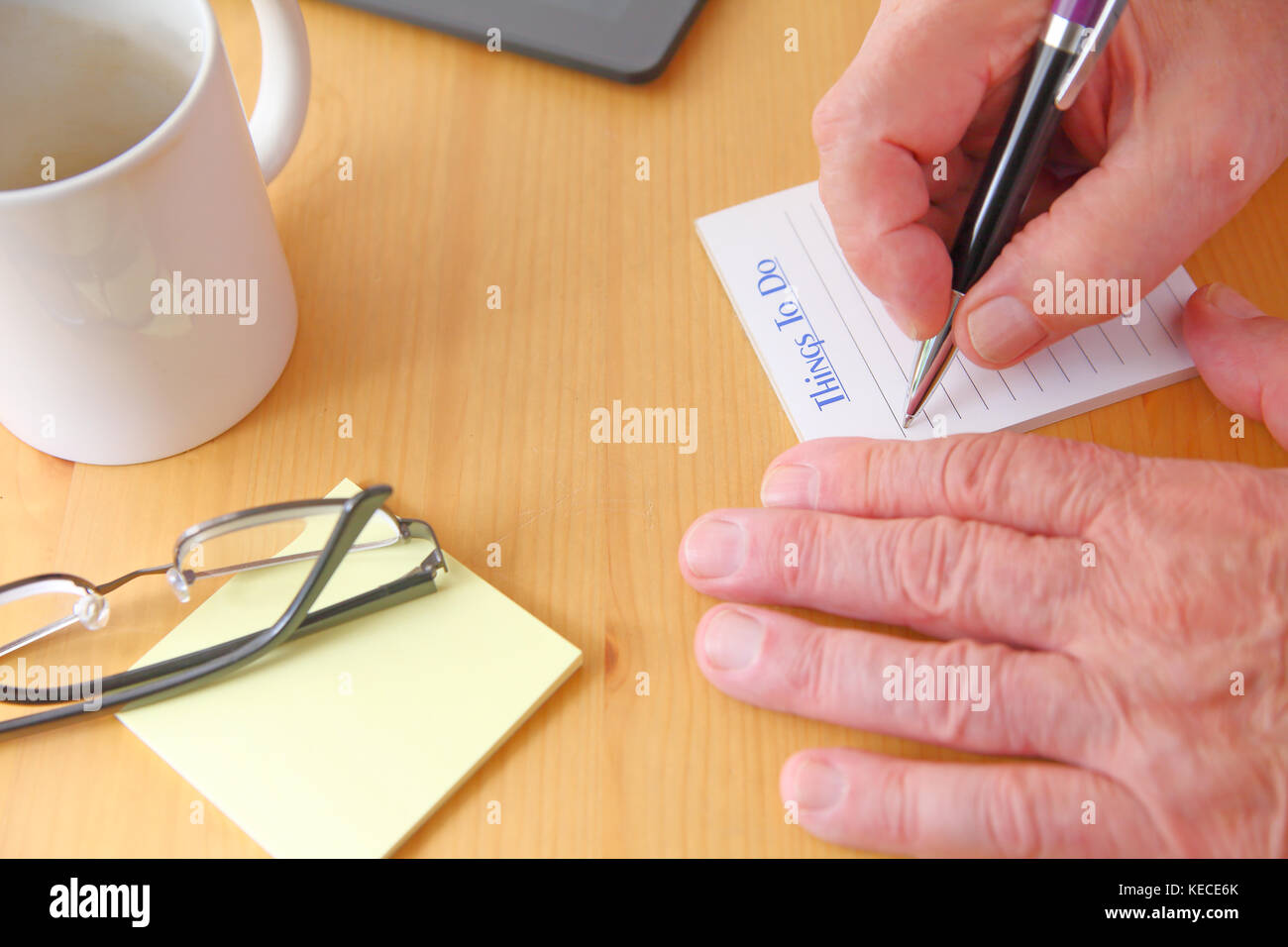 Un homme avec un stylo, lunettes, blocs-notes et tasse de café sur un bureau Banque D'Images
