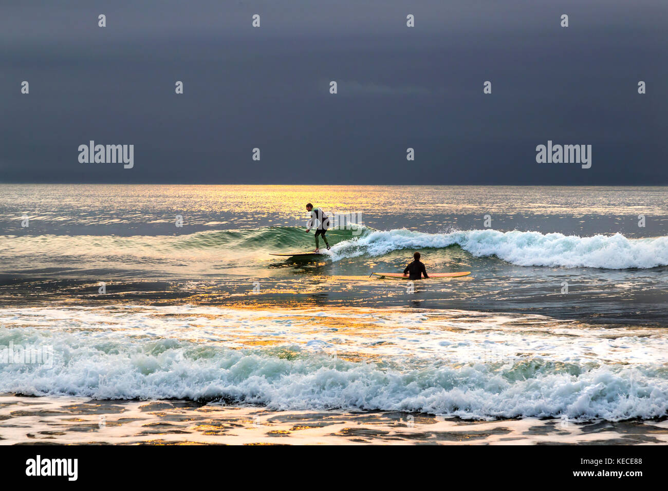 Surf près de la jetée de Bournemouth avec le soleil levant jette une lueur JAUNE SUR L'EAU Banque D'Images
