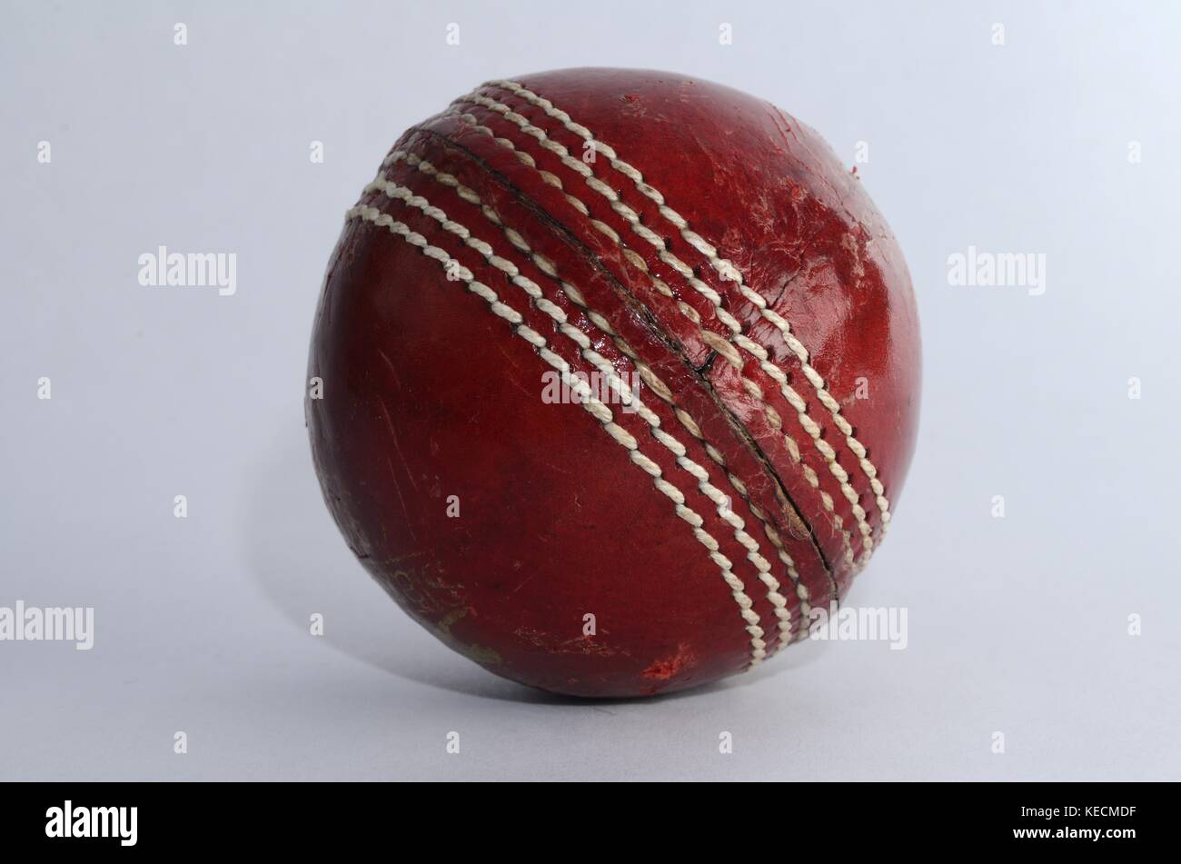 Gros plan d'une balle de cricket anglais rouge classique sur fond blanc Banque D'Images