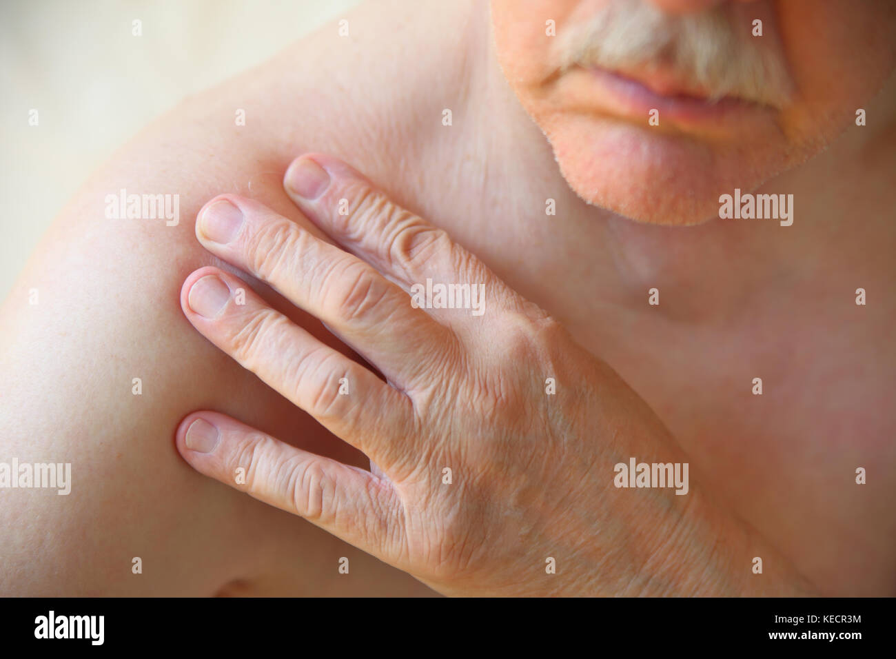 Un homme avec sa main sur une épaule douloureuse Banque D'Images