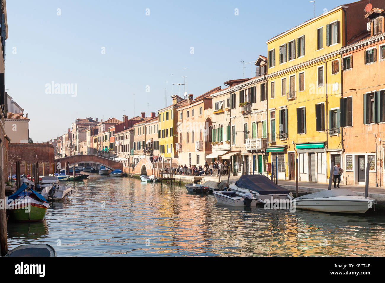 Lumière du soir sur la Fondamenta Ormisini, Cannaregio, Venise, Italie avec reflets dans l'eau potable et les habitants et les touristes à tavernes en plein air Banque D'Images