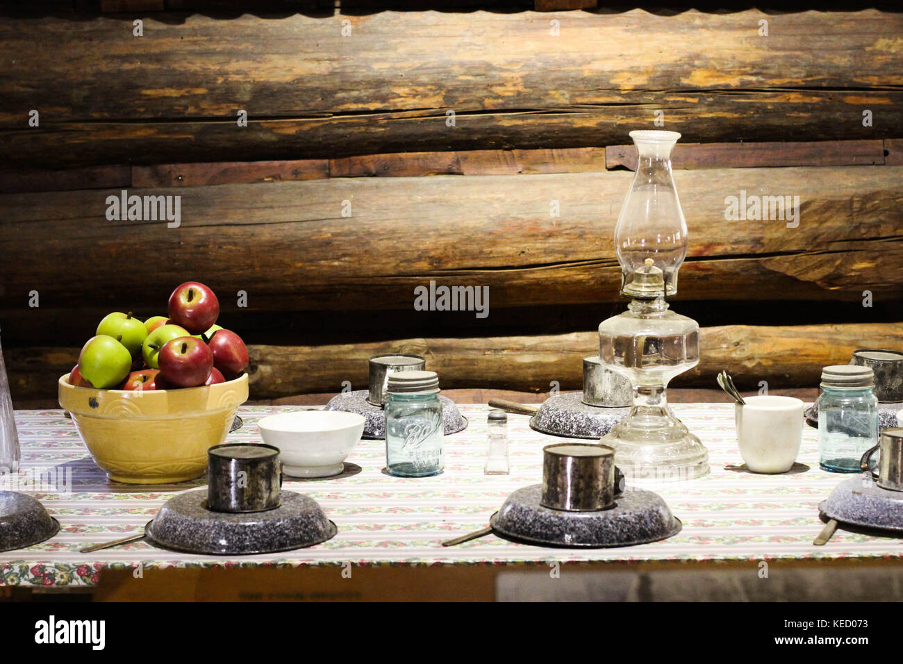 Une vieille table de dîner de la mode est réglé et préparé avec de la nourriture et une lanterne dans une cabane dans un chantier de bois Banque D'Images