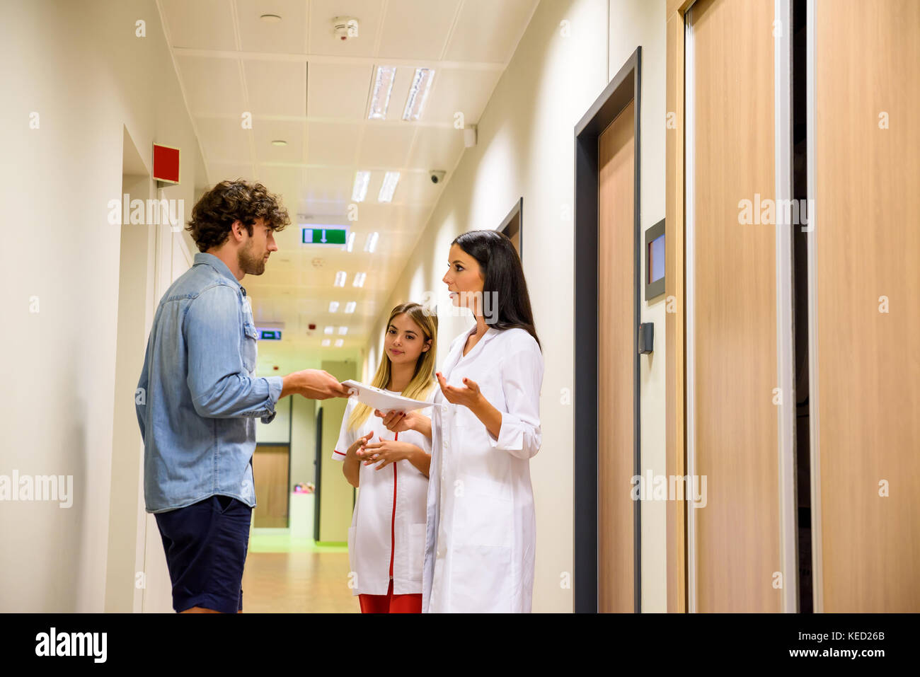 Un médecin et une infirmière du diagnostic avec le patient ou un parent dans l'étage de l'hôpital. Banque D'Images