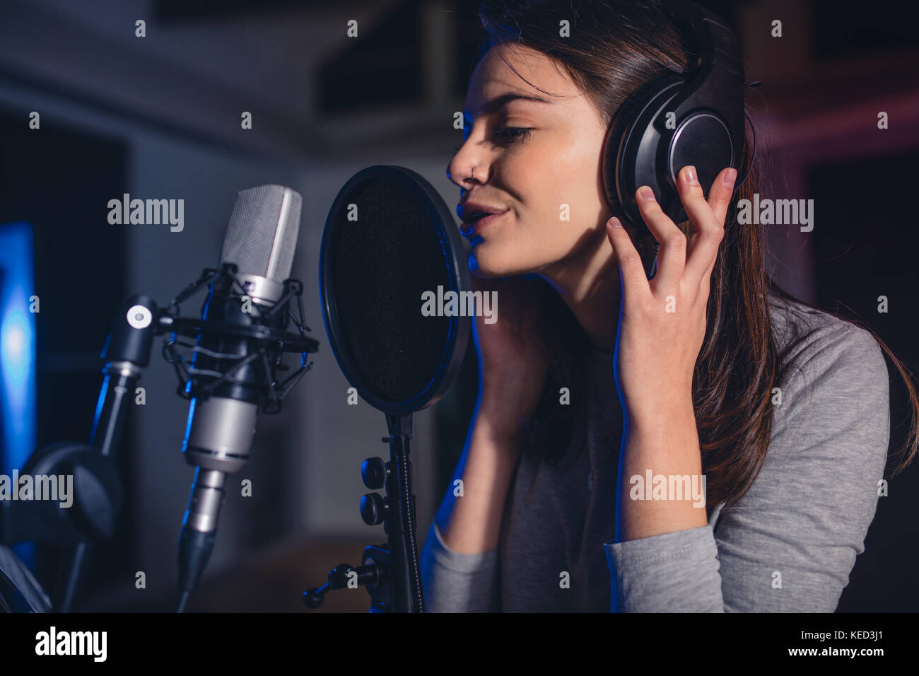 Close up of female vocal artist chanter dans un studio d'enregistrement. Femme chanteuse playback chantant une chanson. Banque D'Images