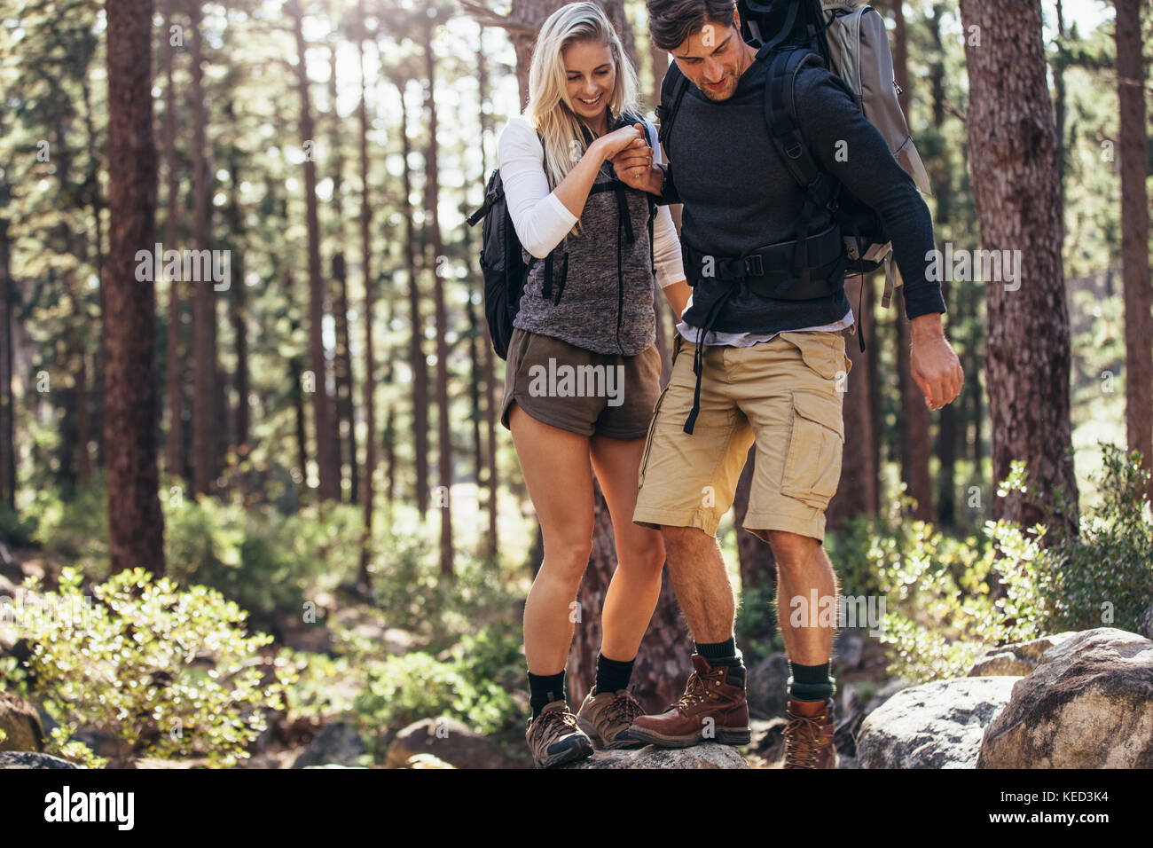 L'homme et la femme les randonneurs randonnée un sentier rocheux en forêt. Couple randonneur tenir la main et marcher avec précaution sur des rochers dans la forêt. Banque D'Images