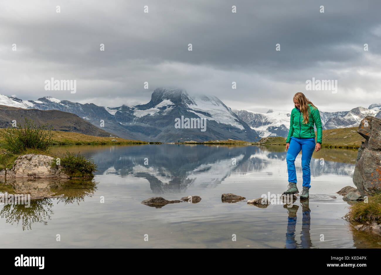 Randonneur marche sur des pierres dans l'eau, stellisee, couvertes de nuages Matterhorn, Valais, Suisse Banque D'Images